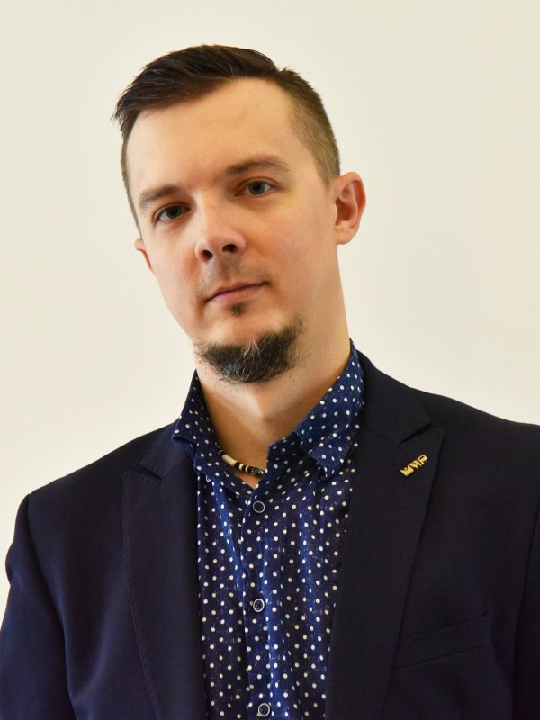 Młody mężczyzna z bródką w granatowej koszuli i marynarce
