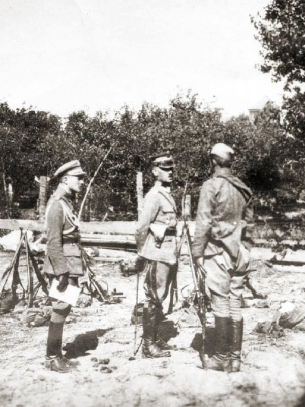 Trzech wojskowych w miejscu obozowania, jeden składa raport generałowi