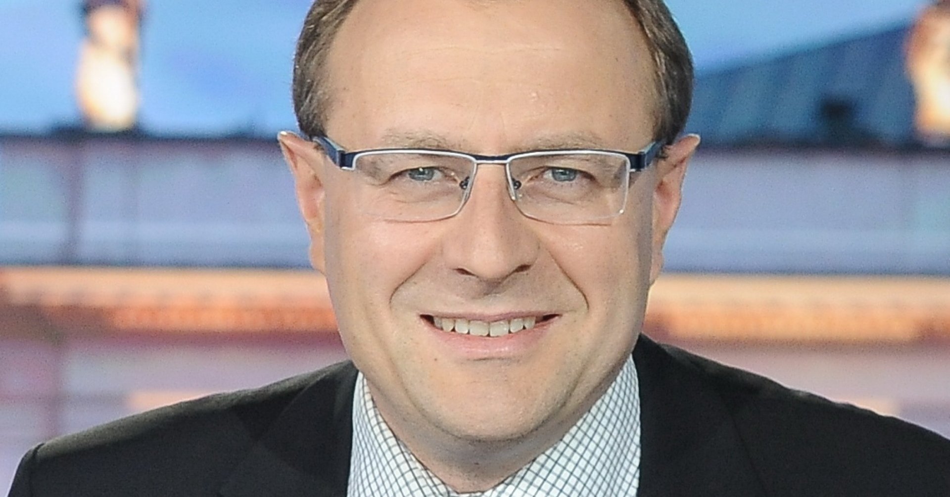 Uśmiechnięty mężczyzna w okularach w garniturze z granatowym krawatem w prążki