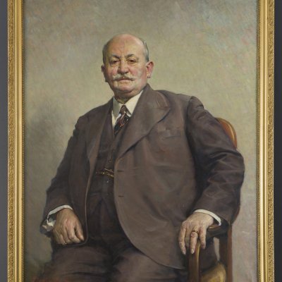  photo of the subject, portrait of a seated middle-aged man with a mustache, dressed in a gray and brown suit