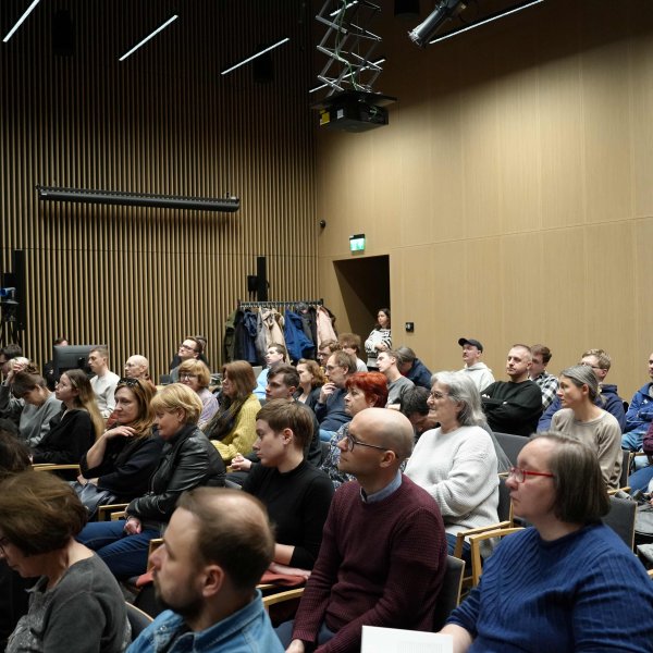 Sala konferencyjna Muzeum wypełniona po brzegi słuchaczami siedzącymi na krzesłach. 