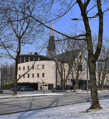 Widok na biały kościół, na pierwszym planie bezlistne drzewa.