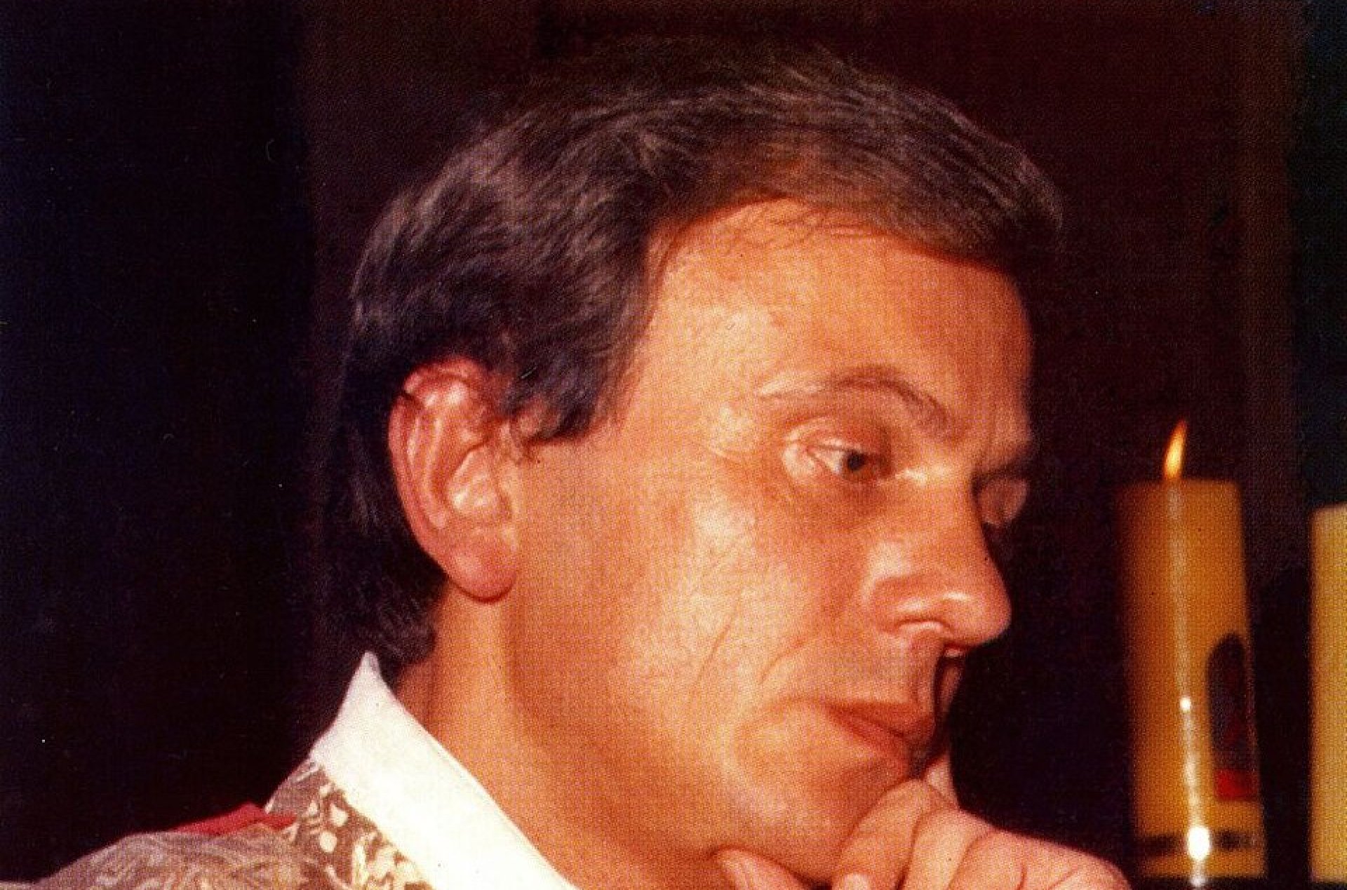 Mężczyzna w średnik wieku, ksiądz w szatach liturgicznych, z brodą podpartą na dłoni w geście zamyślenia,