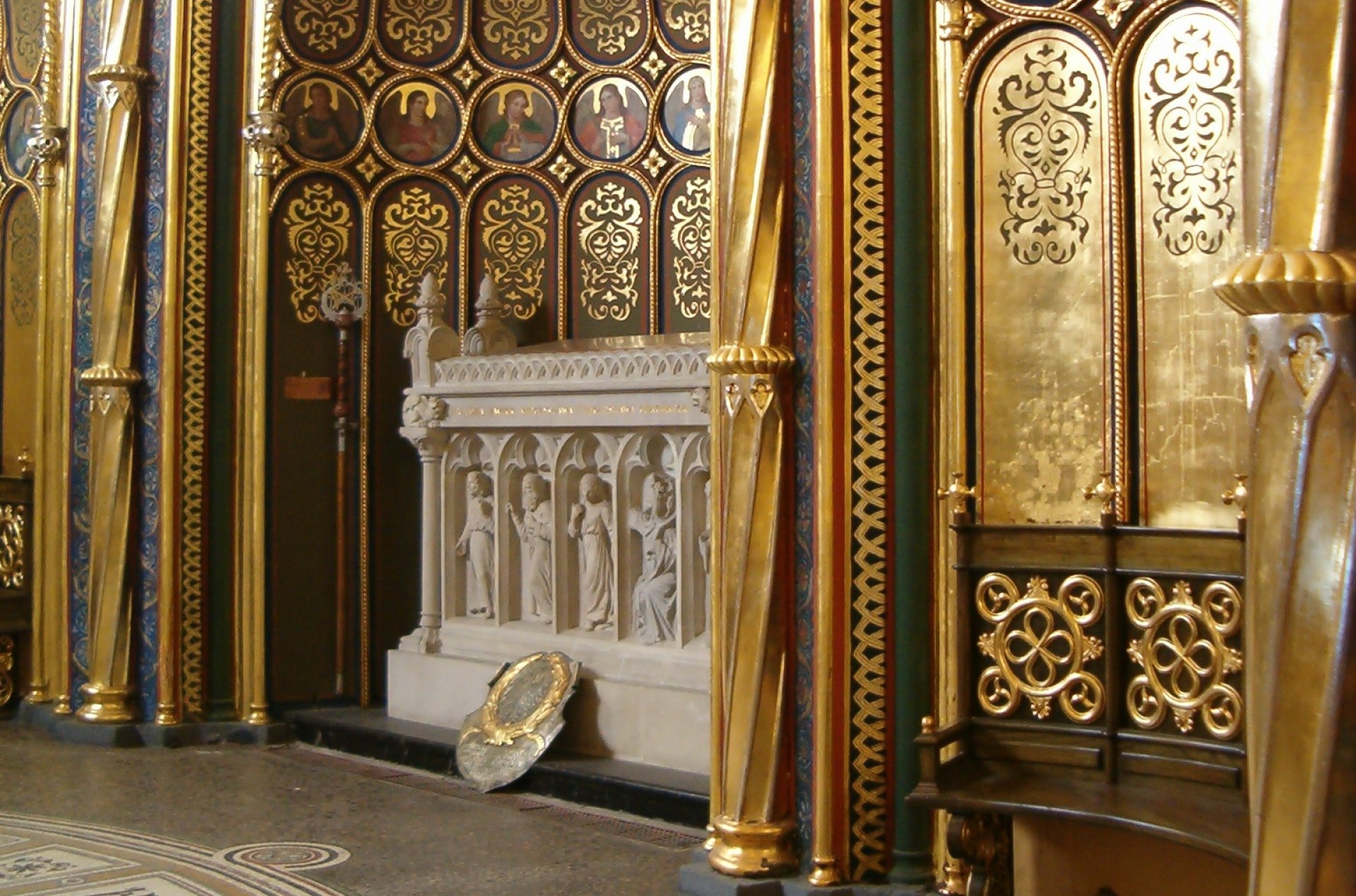 Biały, marmurowy grobowiec w półkolistej złocistej niszy zwieńczonej półkolistym sklepieniem