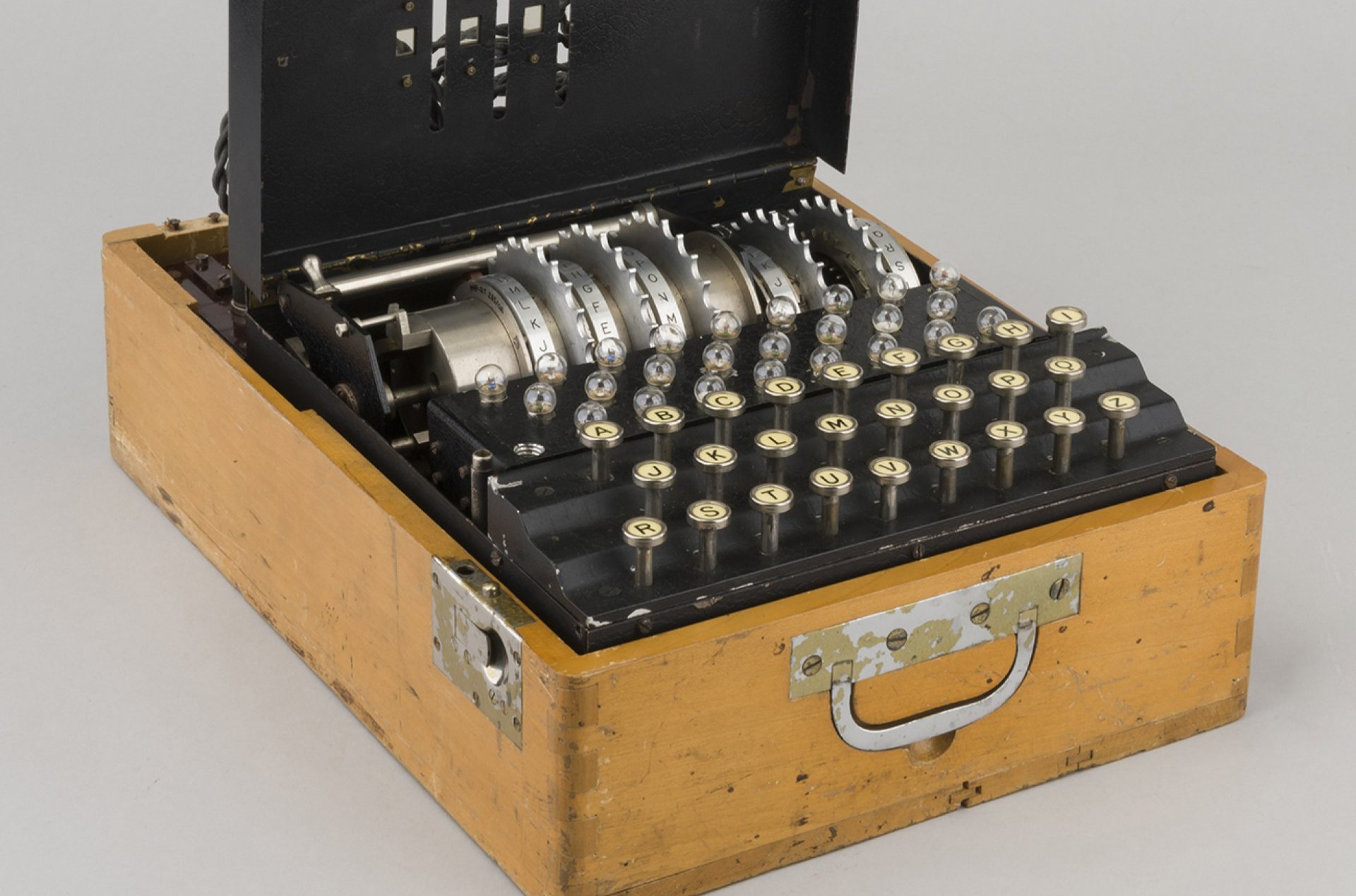 Urządzenie w drewnianej skrzyni, przypominające starą maszynę do pisania.