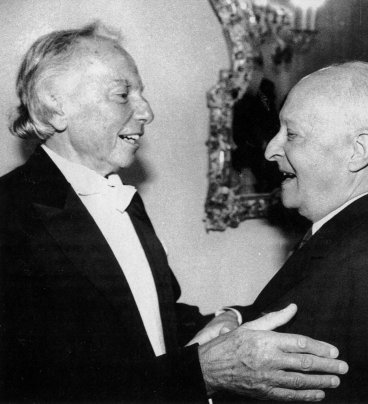 Zdjęcie przedstawia dwóch uśmiechniętych kompozytorów, obejmujących się serdecznie. Obaj są w podeszłym wieku, siwi, łysiejący.