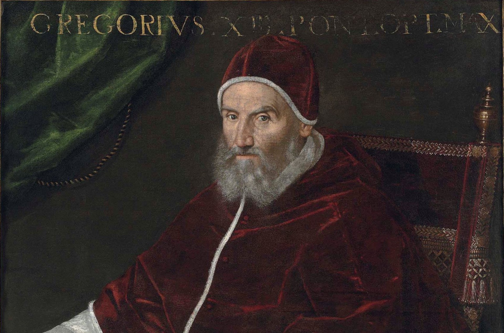 Mężczyzna z siwą brodą, w białych szatach, ciemnoczerwonej pelerynie i nakryciu głowy w tym samym kolorze, siedzi na tronie, w tle ciemnozielona kotara.