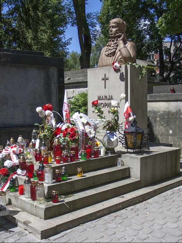 Przyozdobiony kwiatami i lampkami grób z popiersiem pisarki