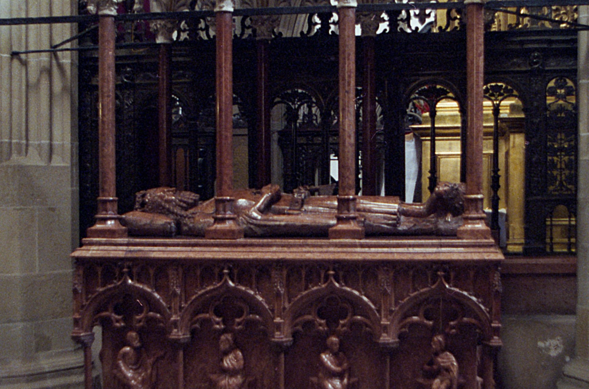 Nagrobek z figurą leżącego króla, z kolumnami i bogatymi zdobieniami.