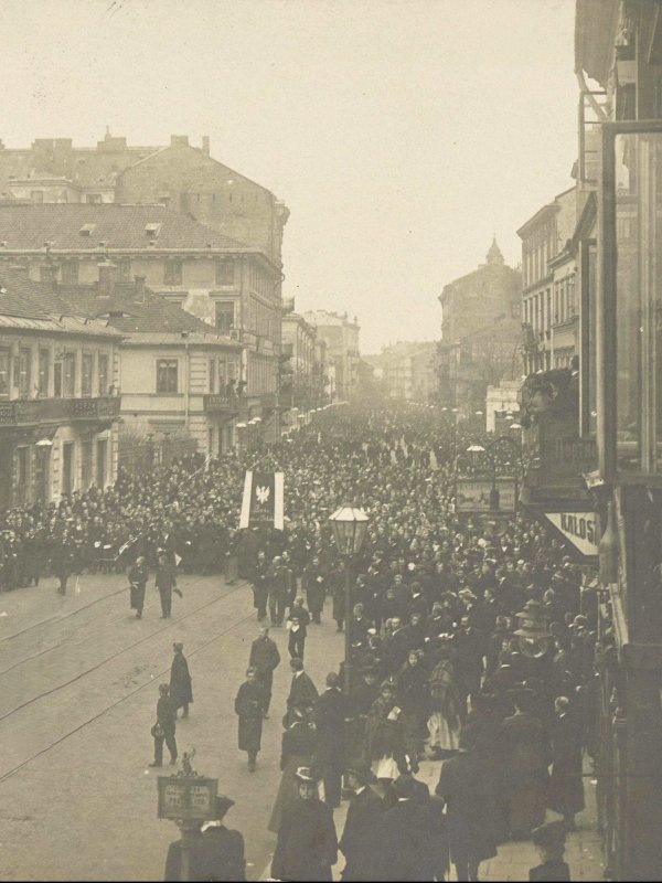 Wielki pochód ze sztandarami idzie warszawską ulicą.