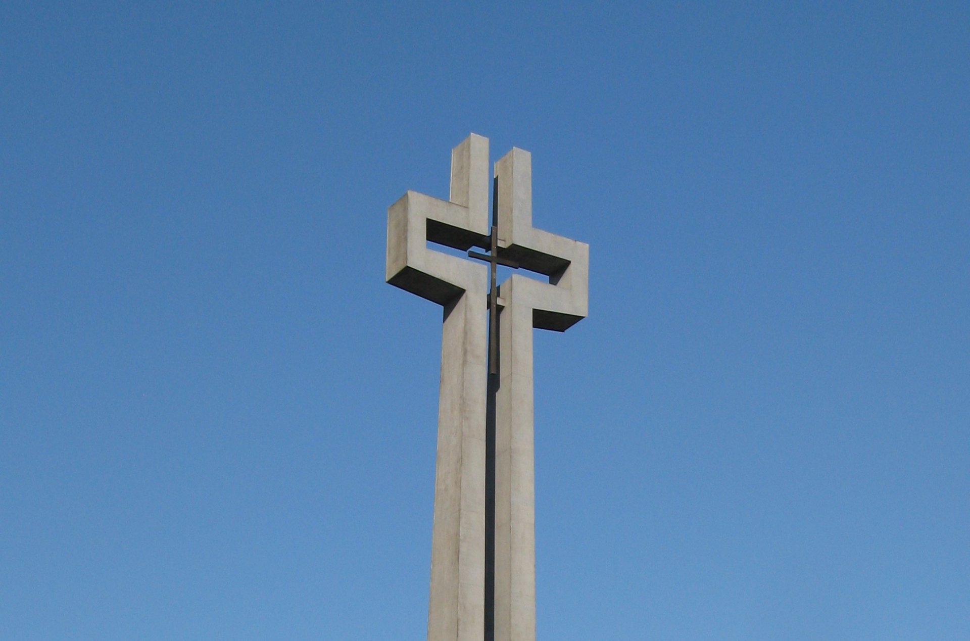Widok na pomnik w kształcie bardzo wysokiego krzyża.