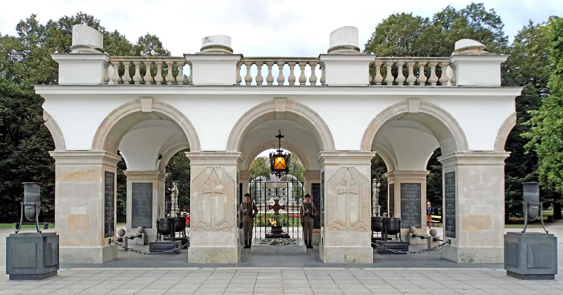 Grób Nieznanego Żołnierza. Widoczna warta honorowa i płonący znicz. W tle - zielone drzewa Ogrodu Saskiego. 