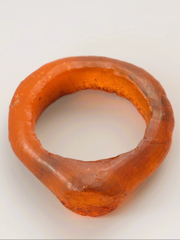 Zdjęcie przedstawia skromny pierścionek wykonany w całości z pomarańczowego bursztynu.