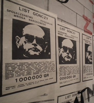 Zdjęcie przedstawia ścianę wyklejoną plakatami - listami gończymi z podobizną Wojciecha Jaruzelskiego.