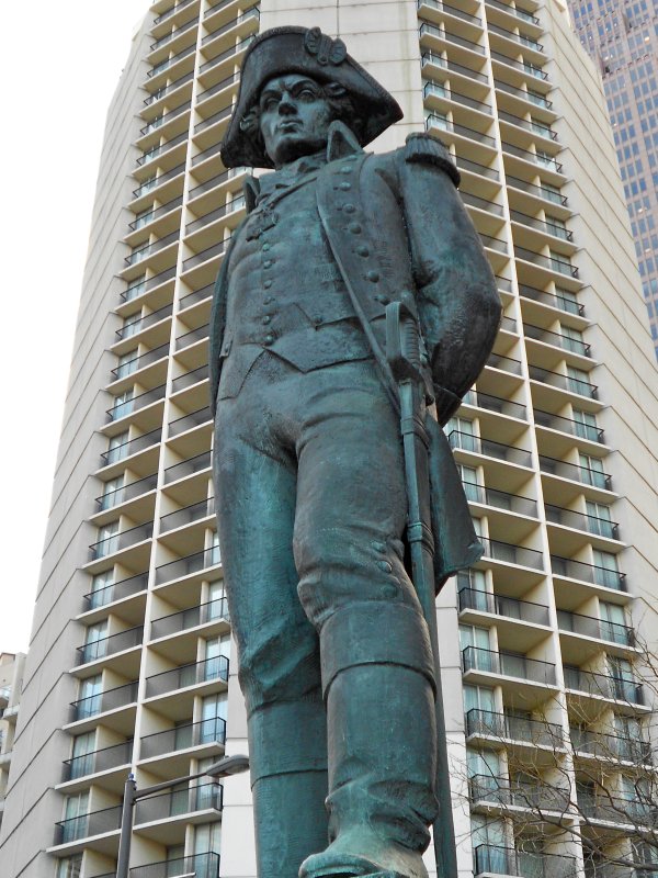 Pomnik przedstawia całą, stojącą postać Tadeusza Kościuszki w mundurze, z szablą przy lewym boku, w bikornie na głowie. W tle - jasny wieżowiec. 