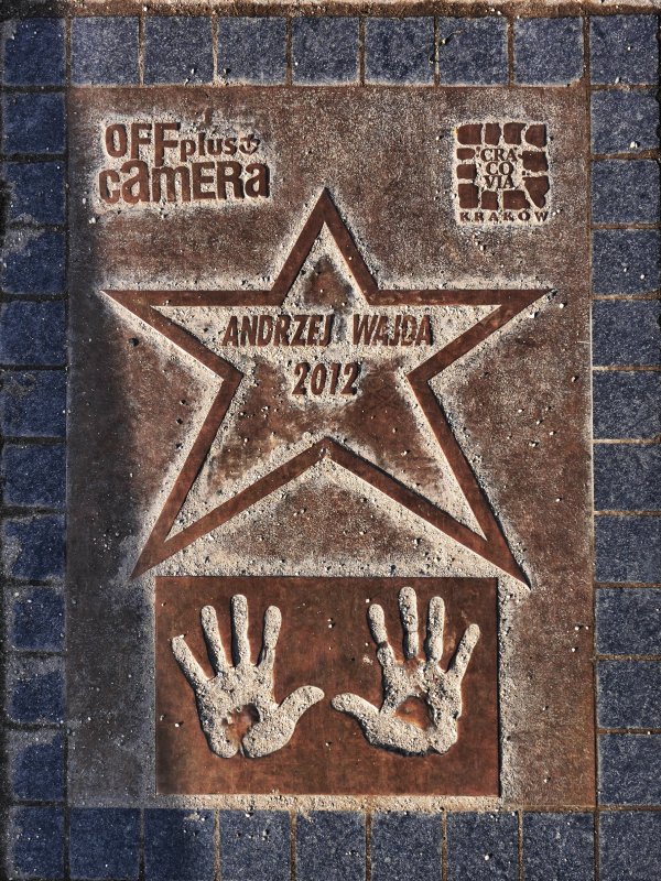 Na tablicy narysowana jest gwiazda, w której widnieje napis: Andrzej Wajda 2012. Pod gwiazdą - dwie odciśnięte dłonie.