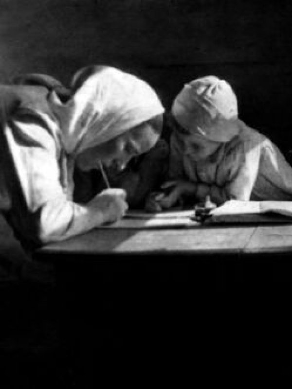 Mama i córka pochylone nad stołem wspólnie odrabiają lekcje.