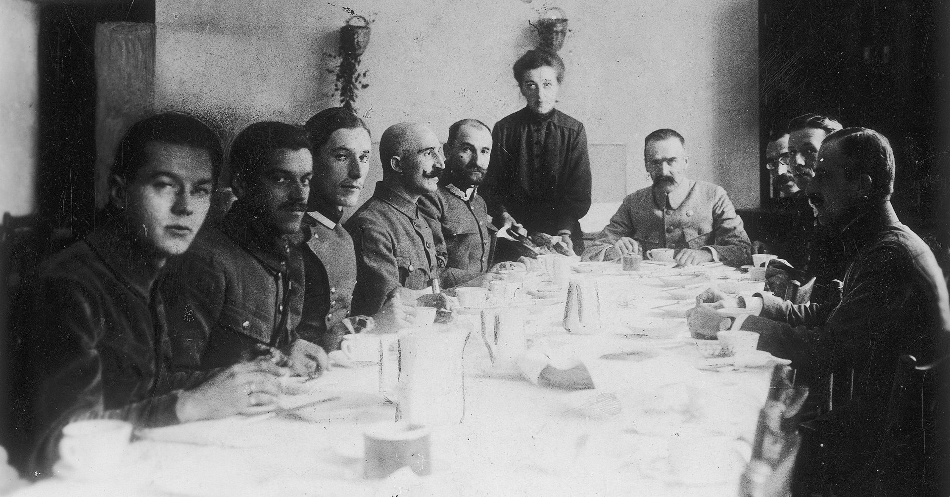 Kilkunastu oficerów w mundurach siedzi przy stole nakrytym białym obrusem. Na honorowym miejscu Józef Piłsudski, po jego prawej stronie - generał Rozwadowski. 