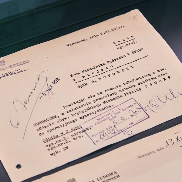 Archiwalny dokument MSW z 1973 roku z klauzulą „Tajne”, dotyczący Micka Jaggera, wyeksponowany w gablocie. Na papierze widoczne są pieczątki, odręczne adnotacje oraz logo Instytutu Pamięci Narodowej.